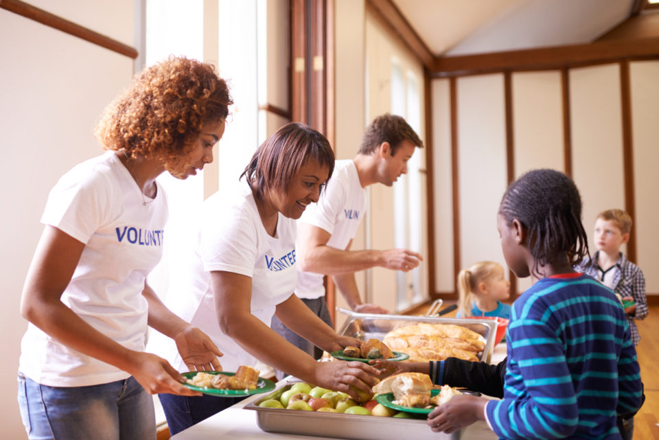group of volunteer workers serving food to children