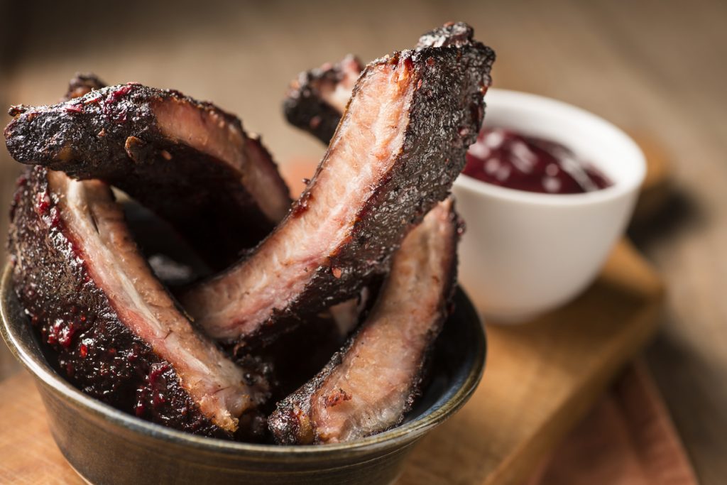A bowl of baby back ribs with barbecue sauce.