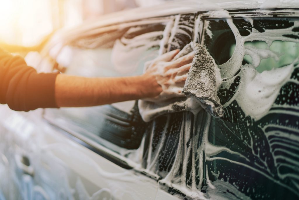 Man cleaning his car with soap and a rag