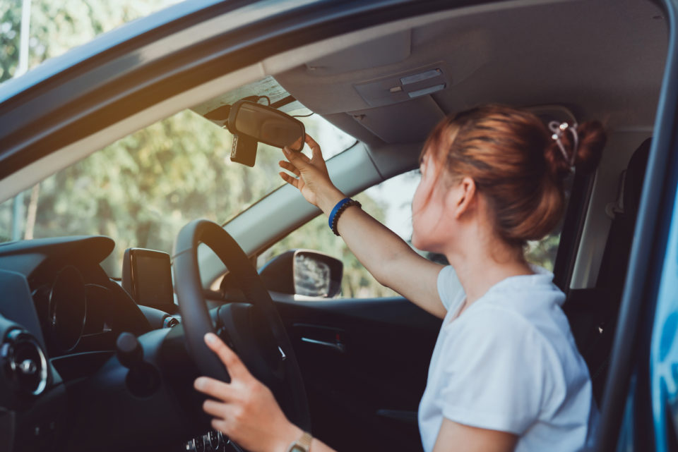 Safety driving woman adjust the car rearview mirror in interior before start travel trip every time.