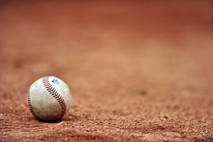 A baseball lies on the gravel outside the dugout prior to a minor league game.